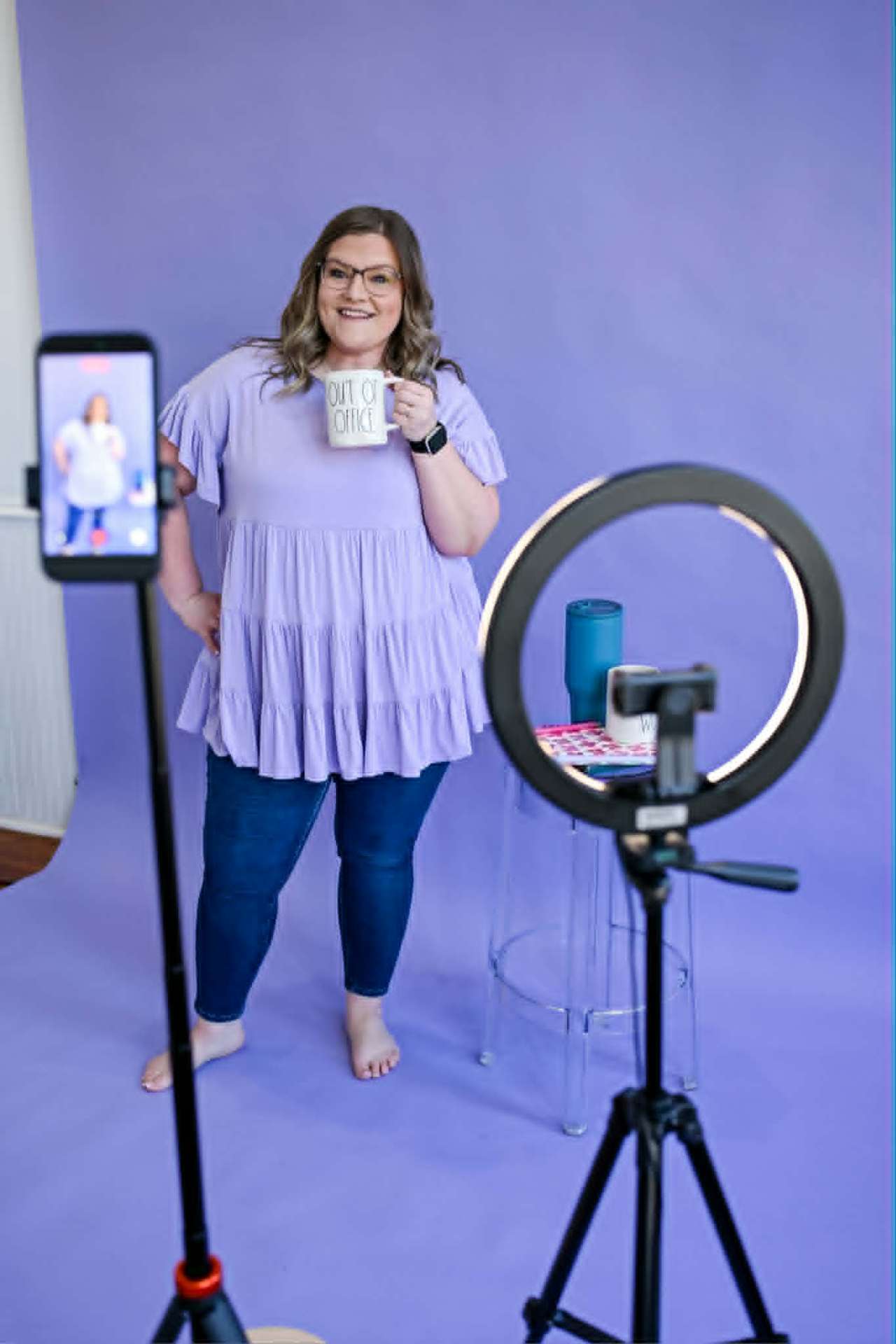 Creator holding a coffee mug in front of a ring light
