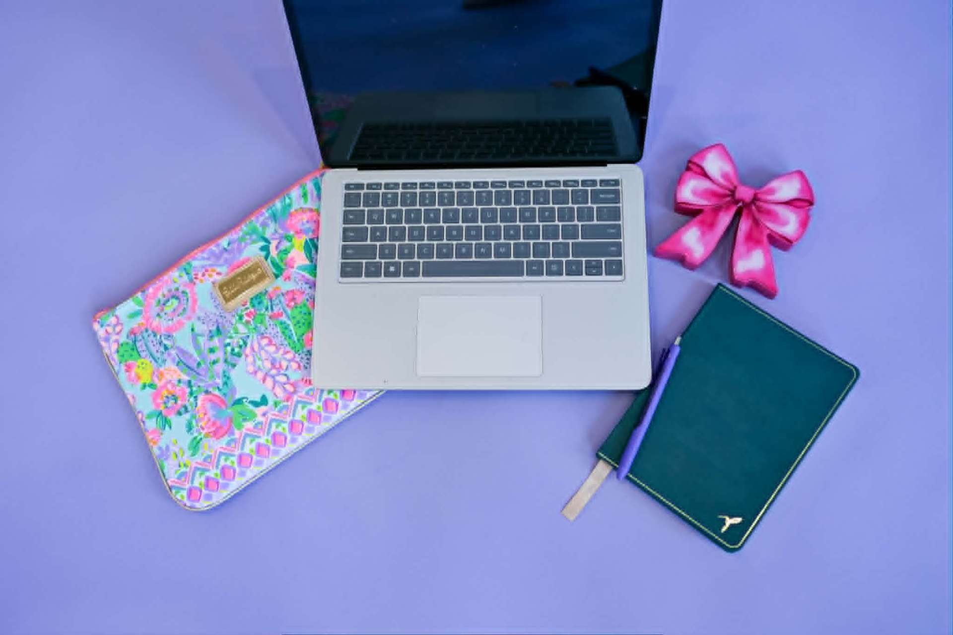 Open laptop and notebook on a calm purple desk